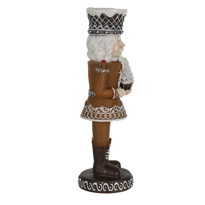 side view of decorative candle nutcracker holding tree cupcake