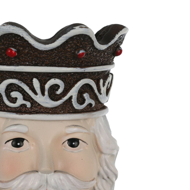 Close-up of a decorative nutcracker head with a crown and beard on a white background