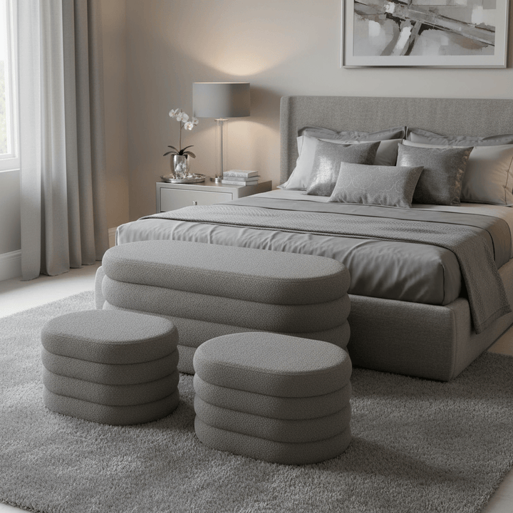 Gray bedroom with bed, ottomans, and side table.
