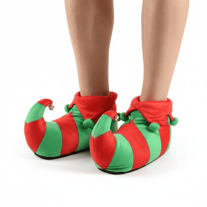 Red and green elf-style slippers worn by a person on a white background