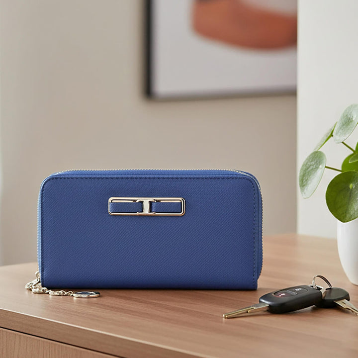 Blue purse on a wooden table with keys and a plant in the background